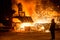 Steelworker near a blast furnace with sparks.