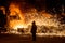 Steelworker near a blast furnace with sparks.