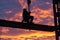 steelworker perched high with sunset skies behind