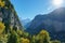 Steep alpine mountains descend to a shadowy valley and the town of Lauterbrunnen, with lens flare