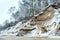 Steep banks in the snow, destruction of the sea shore in winter