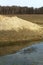 A steep clay bank of a small reservoir. Forest in the background. Landscape