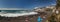 Steep high lava rock cliffs. Turquoise ocean rests on a bright blue sky and a line of clouds above the horizon. Playa Arena beach