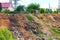 A steep hillside sloping down to the river littered with trash thrown by locals in the village. Slopes in village construction