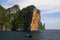 Steep red rock wall rising from water into blue sky of tropical island Ko Phi Phi, Andaman sea, Thailand
