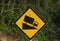 Steep road sign witah a truck driving down a steep downgrade in black and yellow on rainforest backgroundSteep road sign with a tr