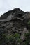 Steep rock with holes. Interesting rock formation, top of mountain in close up. Rock has unusual curved shape. Place in forest for