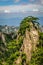 Steep rock with trees covering it and mountain ranges in the distance at Huang Shan é»„å±±, Yellow Mountains in China