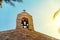 Steeple on top of roof of christian orthodox byzantine Greek church. Big bronze bell, and a big white cross, background