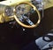 A steering wheel inside a gold custom designed 1950 Ford Model F1 with grey seat covers