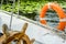 Steering wheel and life buoy on a ship.