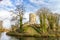 Stein castle ruins with the round tower on a hill, bare trees, moat with calm water