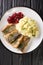 Stekt stromming or fried herring is a hearty Swedish food with boiled potatoes closeup in the plate. Vertical top view