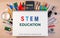 STEM education text on notebook over school supplies or office s