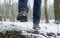 Step forward in winter forest. Male legs in boots walking