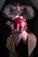 Stepmother witch gives poisoned red apple.Woman as witch in black offers red apple as symbol of temptation, poison.