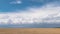 Steppe against blue sky with floating white clouds, time lapse