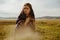 in the steppe sits with the face of a sad and doomed girl in an ethno rakidka against a backdrop of hills in the