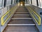 A stepped ramp with yellow handrails gives access to a station platform on a regional rail network