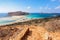 From the steps opens an incredible view on a landscape with a sea of azure color, a sand and mountain beach. A moored ship.