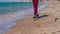 Steps of a teenager in sneakers on the beach near the water