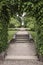 Steps thru arch to formal landscaped gardens