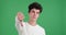 Stern caucasian man showing thumbs down in disapproval on green background