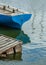 The stern of an old wooden boat moored at the pier, and reflection