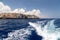 Stern wave of a motor boat with the motor in foreground and the rocky coastline on the eastside of Greek island Rhodes in the