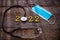 Stethoscope with 2022 number and medical mask on wooden  background. Happy New Year for health care .