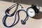 Stethoscope and alarm clock on a wooden table in the sunlight. A tool for measuring blood pressure. Desktop cardiologist