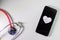 Stethoscope and black smartphone with a heart symbol and heartbeat to show digital doctors office, digital diagnosis