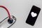 Stethoscope and black smartphone with a heart symbol and heartbeat to show digital doctors office, digital diagnosis