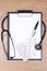 Stethoscope, blank clipboard, pen and pills