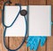 Stethoscope, blank page notepad and gloves on the doctor table. Medical diagnosis or doctor prescription mockup