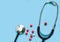 Stethoscope on a blue background with pills and a red heart, free space.