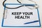 Stethoscope, clip board with text Keep Your Health and blue pen