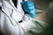 Stethoscope on a doctor`s neck being held by a hand in a blue medical glove. Reflections of a nurse in a sterile mask at a