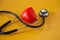 Stethoscope doctors and red heart cardiology placed on a Yellow table in the hospital,  concept: diagnostics disease health presc