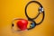 Stethoscope doctors and red heart cardiology placed on a Yellow table in the hospital,  concept: diagnostics disease health prescr