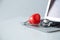 Stethoscope doctors and red heart  placed on a white desk with  laptop background hospital, concept: diagnostics disease health pr