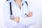 Stethoscope at female doctor breast at hospital office. Unknown physician`s hands close-up. Medicine and health care