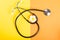 Stethoscope and flower on yellow and orange background
