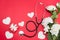 Stethoscope, gift box, heart and white roses on red background. copy space