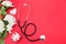 Stethoscope, gift box and white roses on red background. copy space