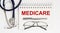 Stethoscope,glasses and pen with notepad with text medicare