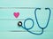 Stethoscope and heart on a blue wooden table. Cardiology equipment for diagnosing cardiovascular diseases. Top view. Flat lay.