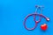 Stethoscope and heart for diagnostic and cure of heart disease on blue background top view mockup