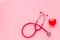 Stethoscope and heart for diagnostic and cure of heart disease on pink background top view mockup