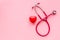 Stethoscope and heart for diagnostic and cure of heart disease on pink background top view mockup